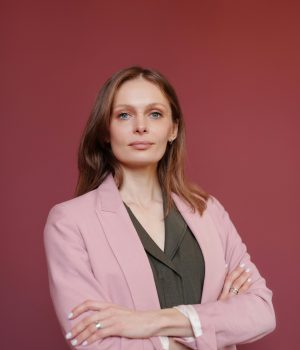 Elegant businesswoman with arms crossed in studio portrait, showcasing leadership and confidence.